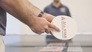 Ping Pong focus on paddle with All Star Healthcare Solutions logo